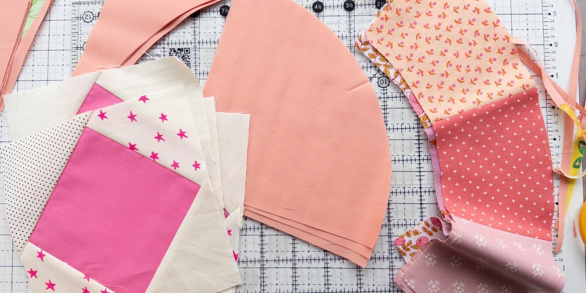 Scrappy Moonbeam baby quilt blocks in shades of pink and white next to clear acrylic Moonbeam templates on a gridded cutting mat