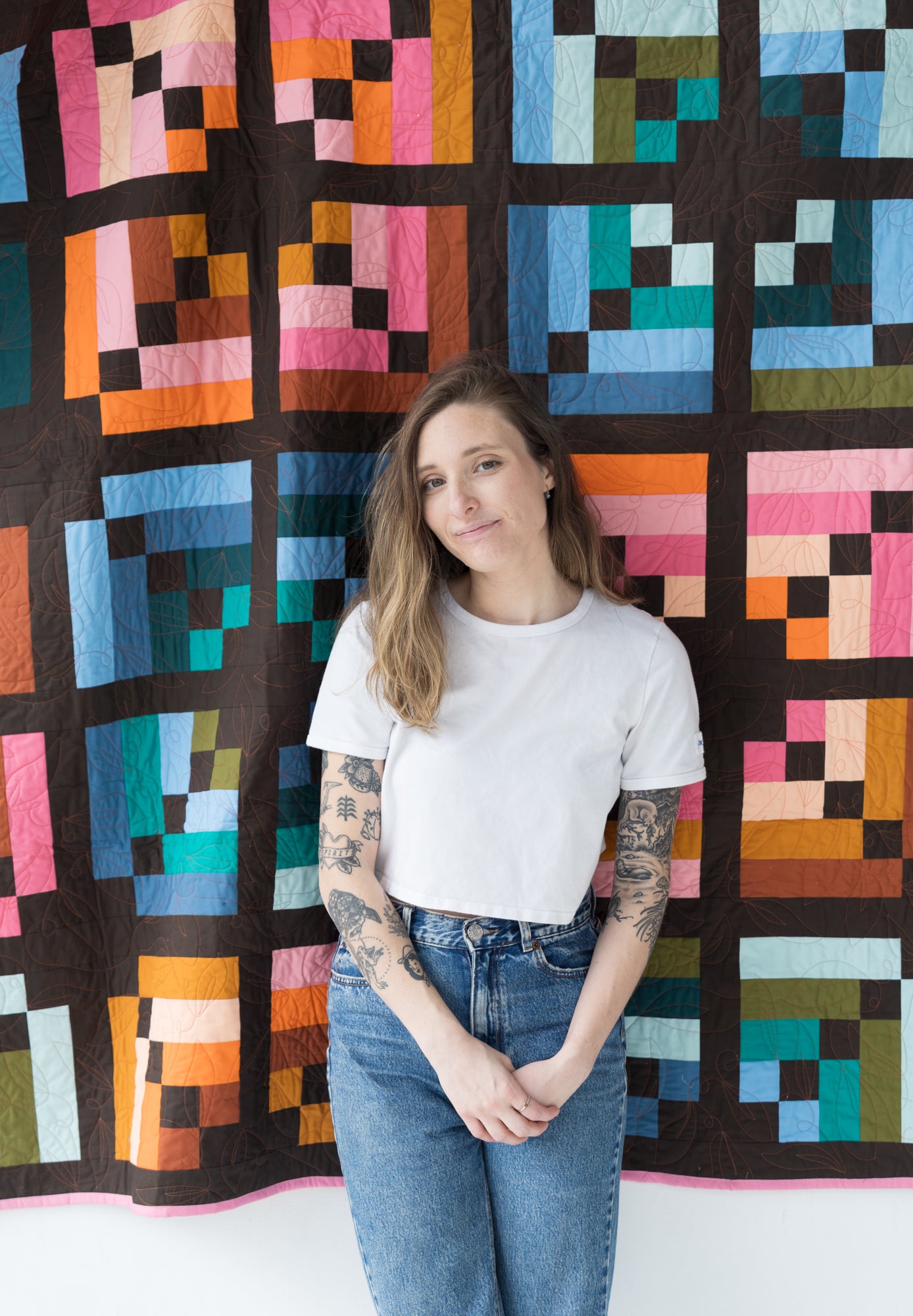 Woman standing in front of a colorful geometric quilt